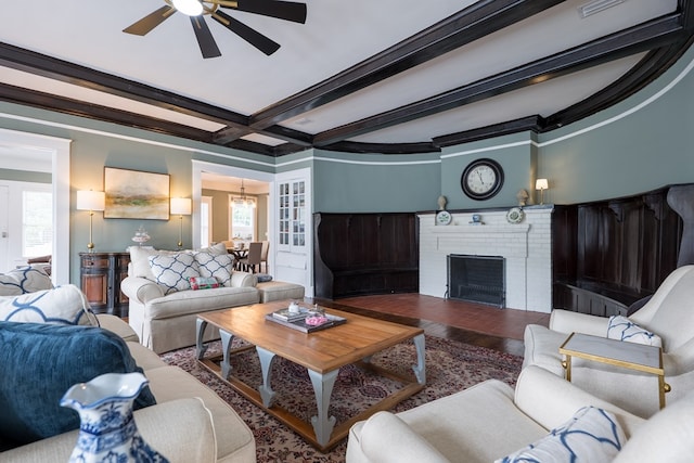 living room with ornamental molding, ceiling fan, beamed ceiling, a fireplace, and hardwood / wood-style floors