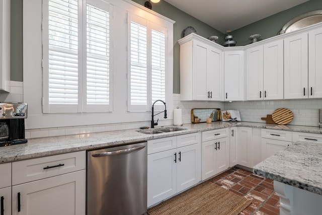 kitchen featuring light stone counters, sink, white cabinets, and stainless steel dishwasher