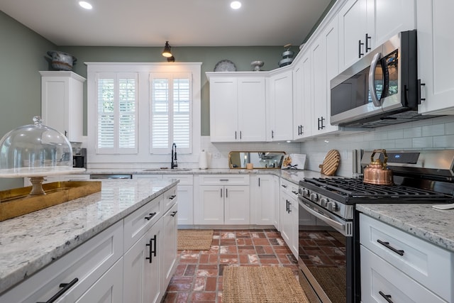 kitchen with sink, decorative backsplash, light stone countertops, appliances with stainless steel finishes, and white cabinetry