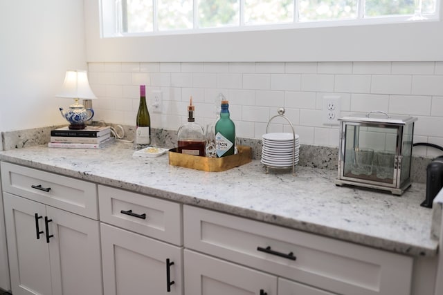 details featuring decorative backsplash, white cabinetry, and light stone countertops