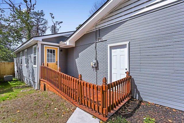 entrance to property featuring brick siding and fence