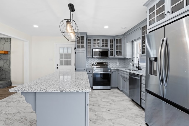 kitchen with gray cabinetry, a kitchen island, a sink, marble finish floor, and appliances with stainless steel finishes