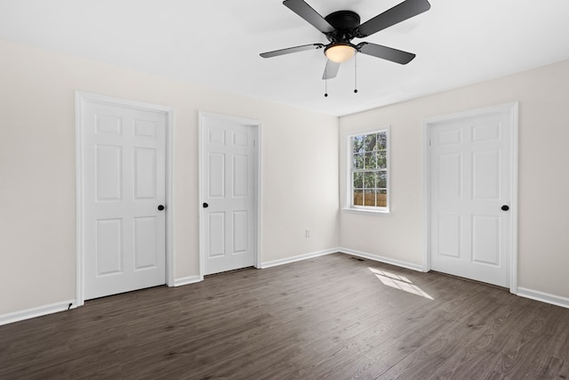 unfurnished bedroom featuring dark wood-type flooring, a ceiling fan, and baseboards