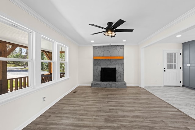 unfurnished living room featuring ornamental molding, a healthy amount of sunlight, a fireplace, and baseboards