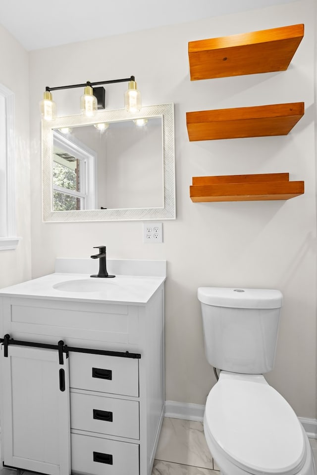 half bath with toilet, marble finish floor, vanity, and baseboards