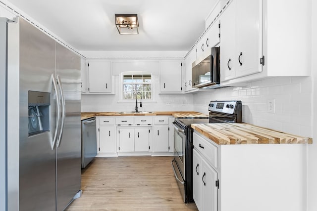 kitchen featuring wooden counters, appliances with stainless steel finishes, a sink, and white cabinetry