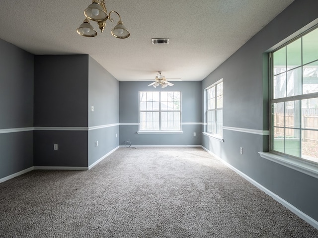 carpeted empty room with ceiling fan with notable chandelier and a textured ceiling