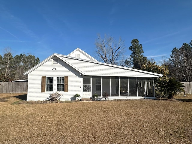 rear view of property featuring a sunroom and a yard