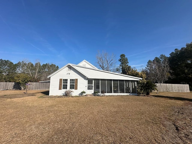 rear view of house with a yard and a sunroom