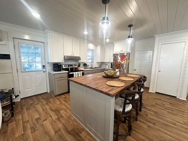 kitchen with white cabinetry, decorative light fixtures, stainless steel appliances, and a kitchen island