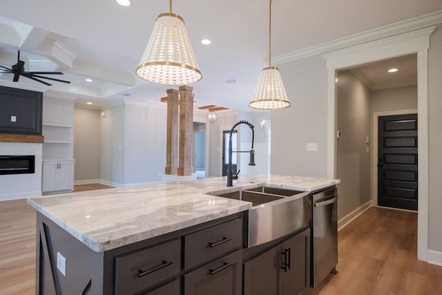 kitchen featuring ornamental molding, sink, an island with sink, and hanging light fixtures