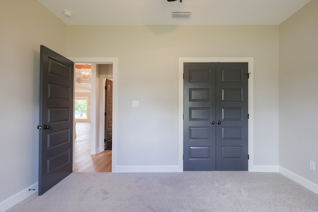 unfurnished bedroom with light colored carpet and a closet