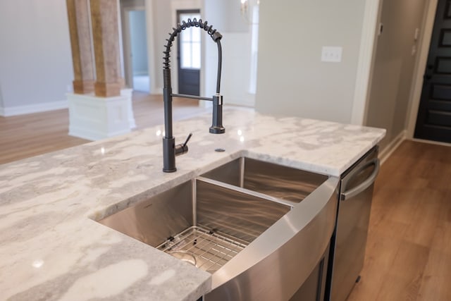 interior details with wood-type flooring, sink, and light stone counters