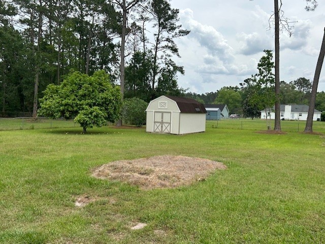 view of yard with fence, an outbuilding, and a storage unit
