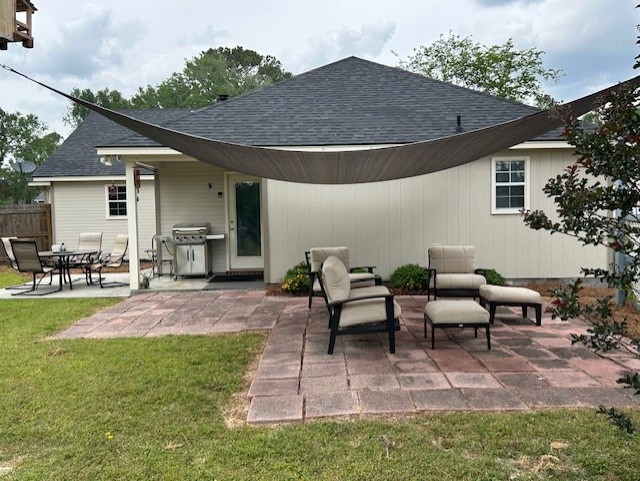 back of property with roof with shingles, fence, a yard, a patio, and an outdoor living space
