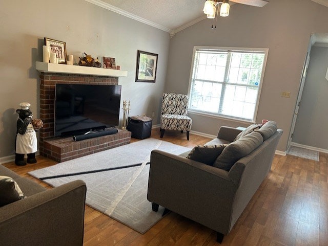 living area featuring lofted ceiling, wood finished floors, a ceiling fan, ornamental molding, and baseboards