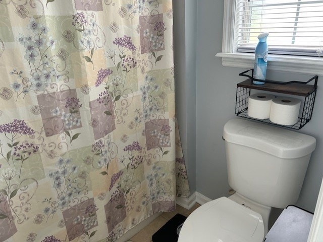 full bathroom featuring baseboards, a shower with shower curtain, and toilet