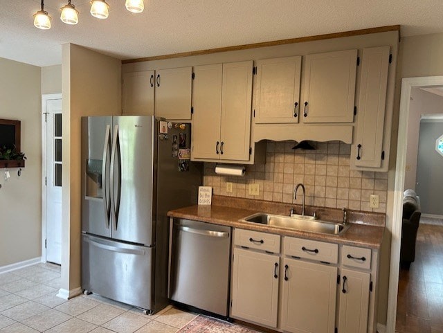 kitchen with dark countertops, a sink, decorative backsplash, baseboards, and appliances with stainless steel finishes