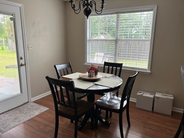 dining area with dark wood-type flooring, baseboards, and a chandelier