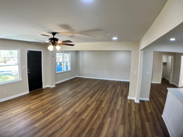 unfurnished living room with dark hardwood / wood-style flooring, ceiling fan, and a healthy amount of sunlight