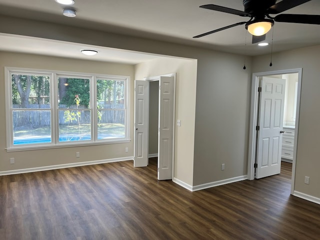 unfurnished bedroom featuring ensuite bathroom, ceiling fan, and dark wood-type flooring