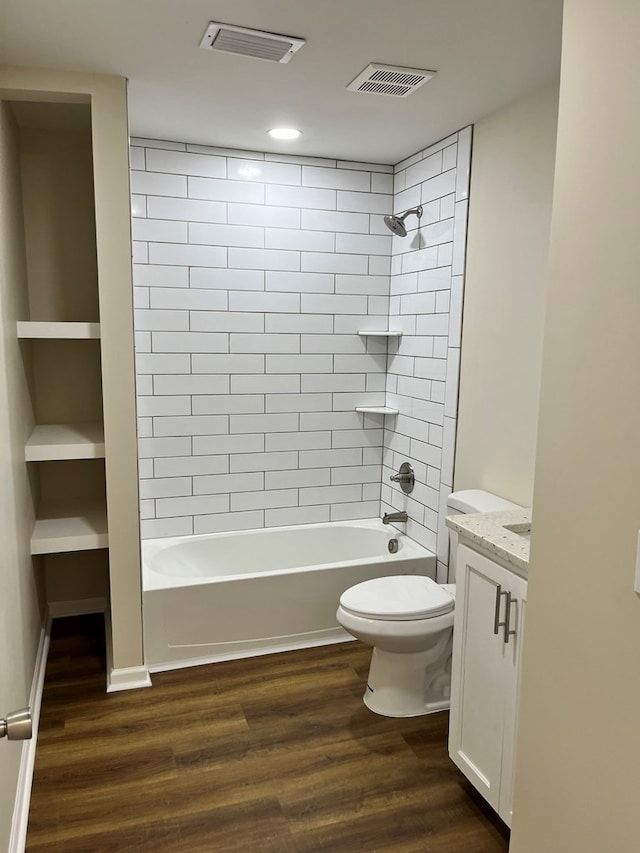 full bathroom with tiled shower / bath, toilet, vanity, and hardwood / wood-style flooring