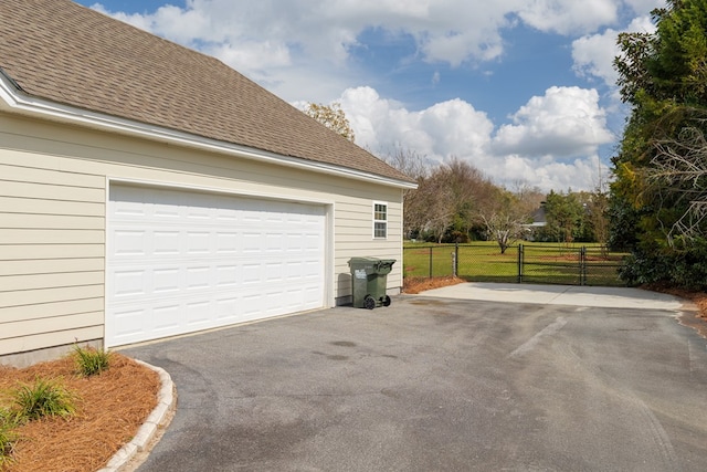 garage featuring aphalt driveway and fence