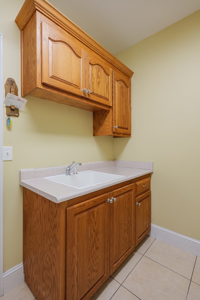 laundry area with light tile patterned floors, a sink, and baseboards