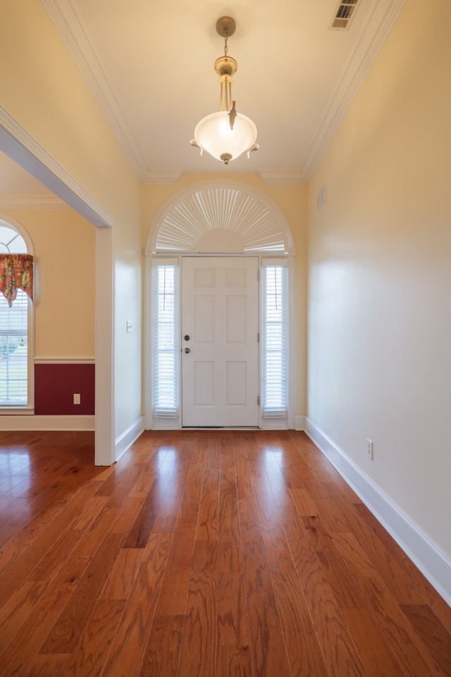 foyer with visible vents, ornamental molding, hardwood / wood-style floors, and baseboards