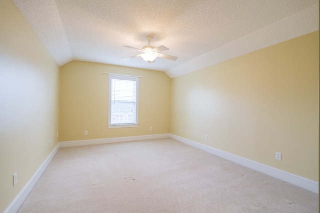 interior space with lofted ceiling, light colored carpet, ceiling fan, a textured ceiling, and baseboards