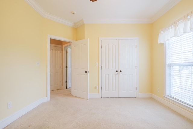 unfurnished bedroom featuring light carpet, a closet, baseboards, and crown molding