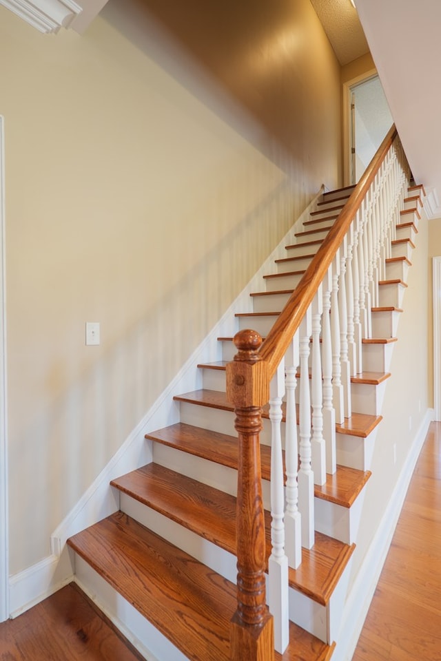 staircase featuring baseboards and wood finished floors