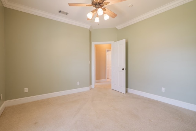 empty room with crown molding, light colored carpet, visible vents, ceiling fan, and baseboards