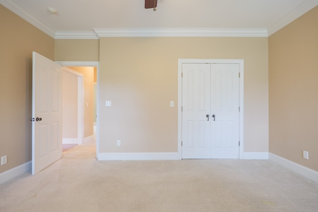 unfurnished bedroom with baseboards, ornamental molding, a closet, and light colored carpet