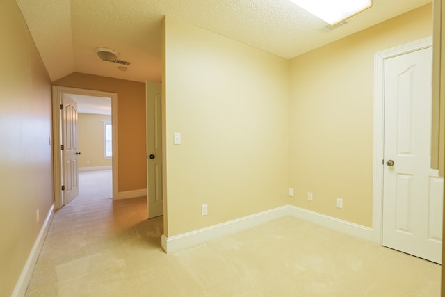 interior space with baseboards, visible vents, light carpet, and a textured ceiling