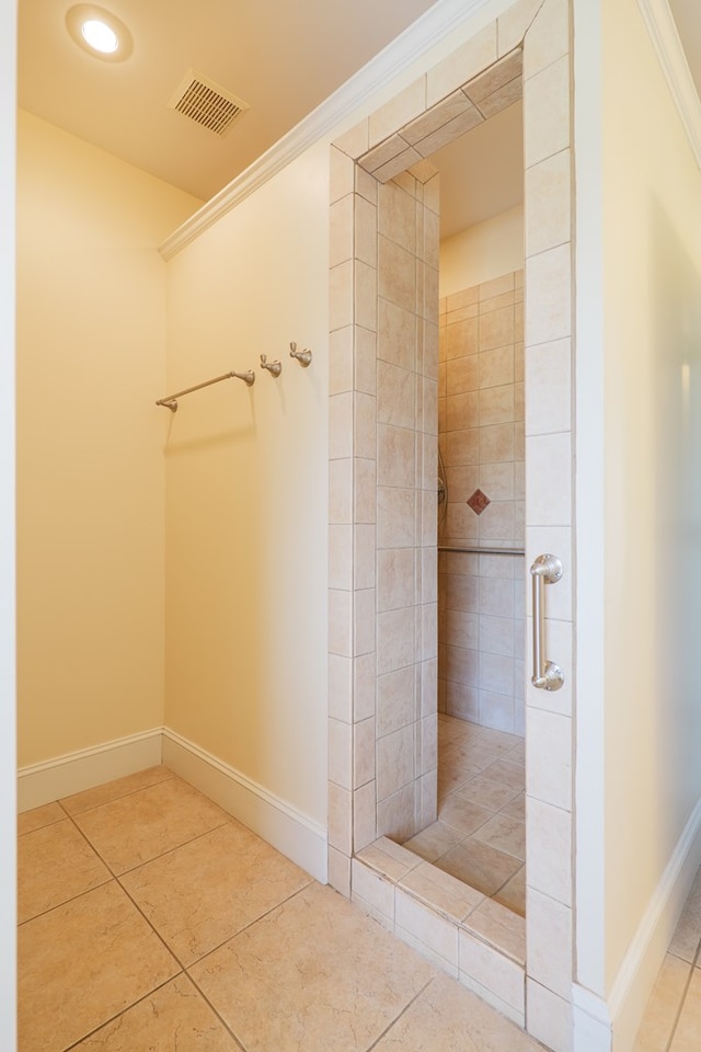 bathroom featuring tile patterned flooring, visible vents, a tile shower, and crown molding