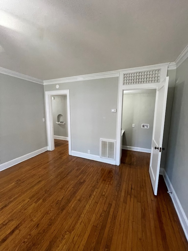 empty room with dark hardwood / wood-style flooring, a textured ceiling, and ornamental molding