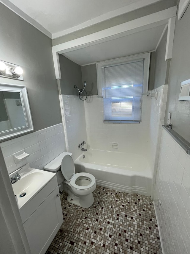 full bathroom featuring tile patterned floors, vanity, tiled shower / bath combo, tile walls, and toilet