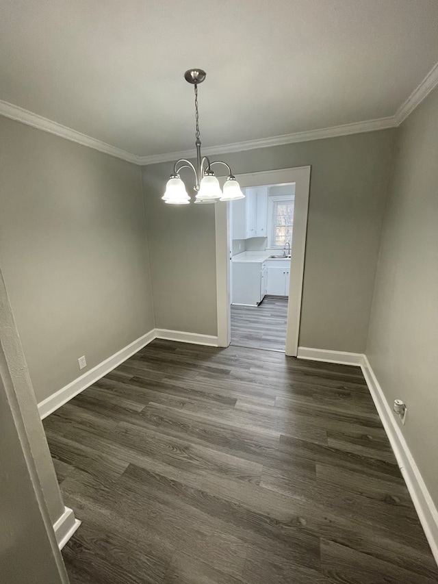 unfurnished dining area with sink, dark hardwood / wood-style flooring, ornamental molding, and an inviting chandelier