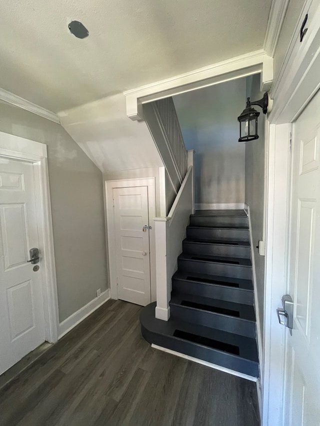 stairs with a textured ceiling, hardwood / wood-style flooring, vaulted ceiling, and crown molding