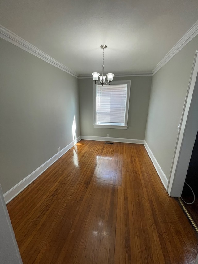 unfurnished dining area featuring wood-type flooring, ornamental molding, and an inviting chandelier