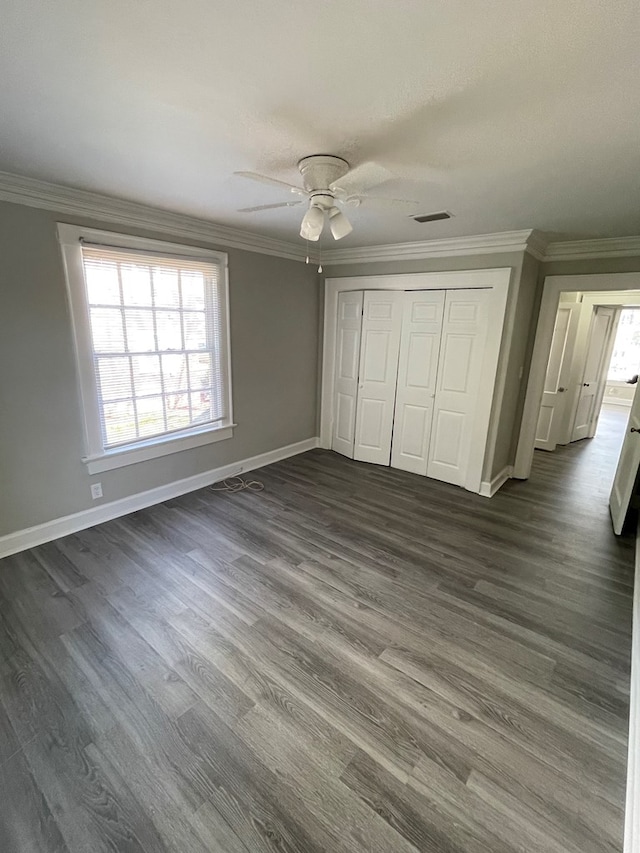 unfurnished bedroom with ceiling fan, dark hardwood / wood-style flooring, ornamental molding, and a closet