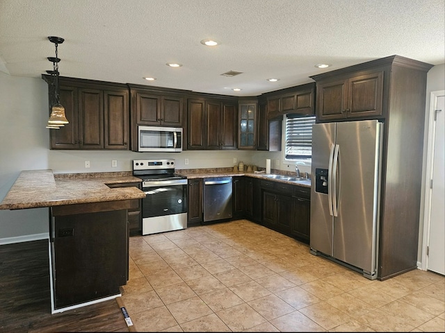 kitchen with dark brown cabinetry, sink, hanging light fixtures, stainless steel appliances, and kitchen peninsula