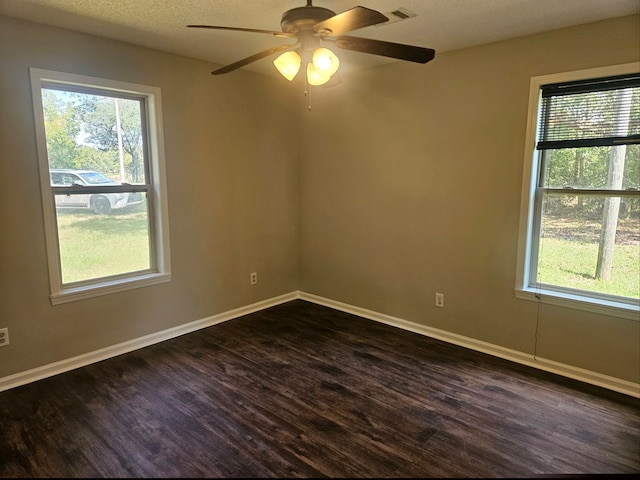 spare room featuring a textured ceiling, a wealth of natural light, ceiling fan, and dark hardwood / wood-style floors