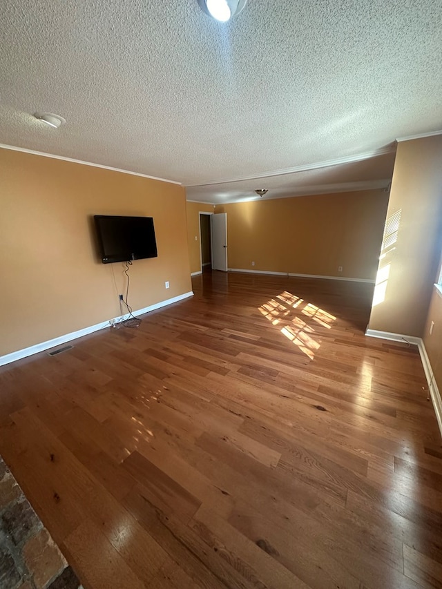 unfurnished living room featuring baseboards, visible vents, wood finished floors, crown molding, and a textured ceiling