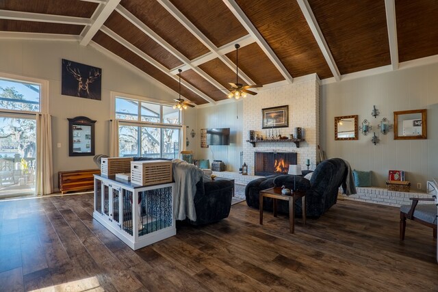 living room with ceiling fan, beamed ceiling, dark wood-type flooring, and a brick fireplace