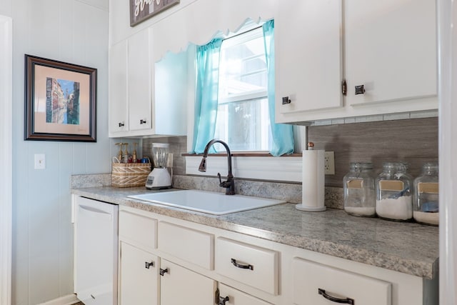 kitchen with white dishwasher, white cabinetry, plenty of natural light, and sink