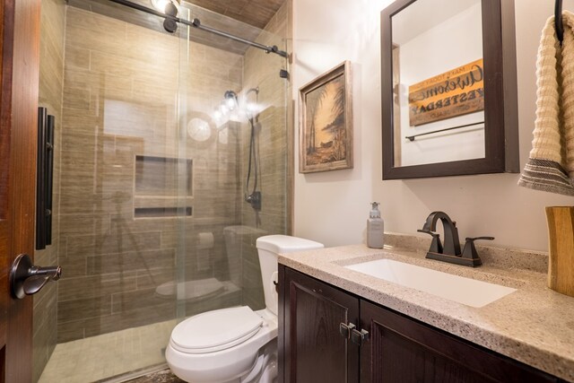 bathroom featuring tile patterned floors, vanity, a shower with shower door, and toilet