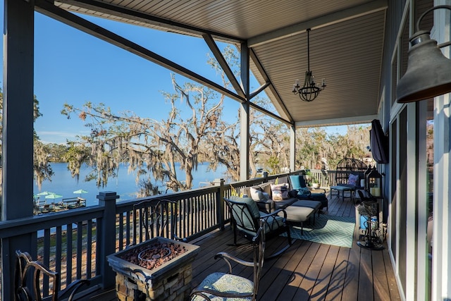 wooden terrace with a water view and an outdoor living space with a fire pit