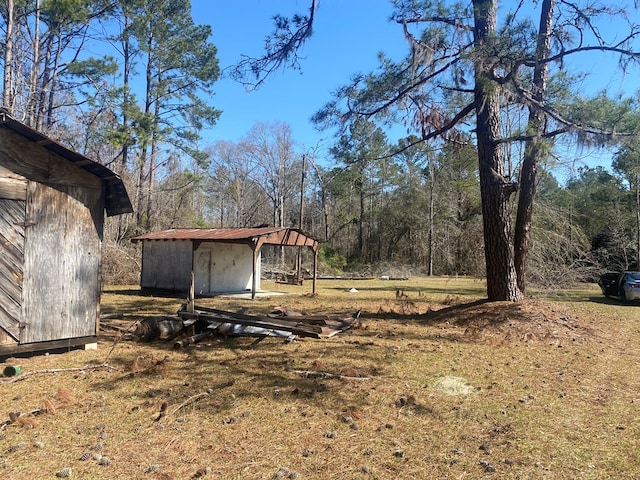 view of yard with a forest view, a storage unit, and an outdoor structure